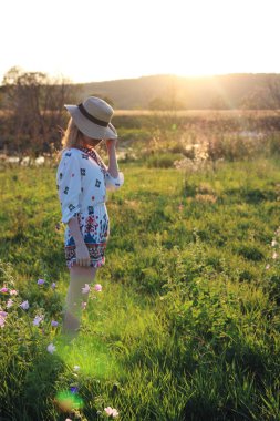 Gün batımıgüneşinde şapkalı kız.