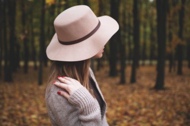 Sonbahar Parkı 'nda yürüyen açık renk şapkalı kız.