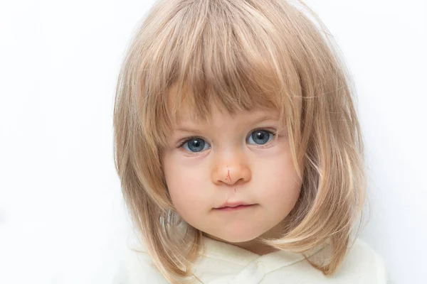 Μπλε-eyed ξανθιά μωρό με Bob μαλλιά και γδαρμένο μύτη close-up. Απομονωμένα σε λευκό. Θηλυκό παιδί ψάχνει σοβαρά σε κάμερα στο λευκό studio, frowning φρύδια. Αρνητικά συναισθήματα, δυσαρέσκεια, αδίκημα. Royalty Free Εικόνες Αρχείου