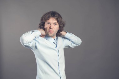 Dalgalı saç gri bir arka plan üzerinde gömlek ve yay kravatlı adam gülümsüyor ve mizahi dili gösterir. Yarı açık-erkek ayakta dilini kameranın içine sıkışmış. Yatay. İzole. Kopya alanı.