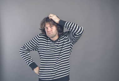 Dağınık saçlı çatık ve tatminsiz seyir şaşkın adam kafa çizilmemesi, derin gri duvar arka planda bir şey düşünüyorum. İnsan yüz ifadesi, duygu, duygu, işaret vücut dili.