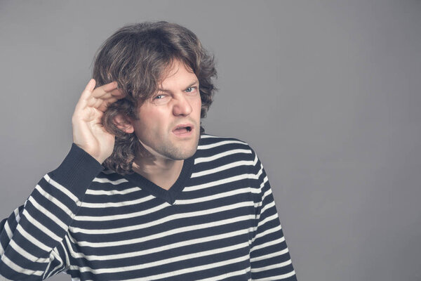 Человек с нарушением слуха пытается услышать хмурый взгляд, когда он держит руку к уху в попытке улучшить акустику. Сплетни. Злой человек держит кого-то за ухо и слушает. Язык тела
