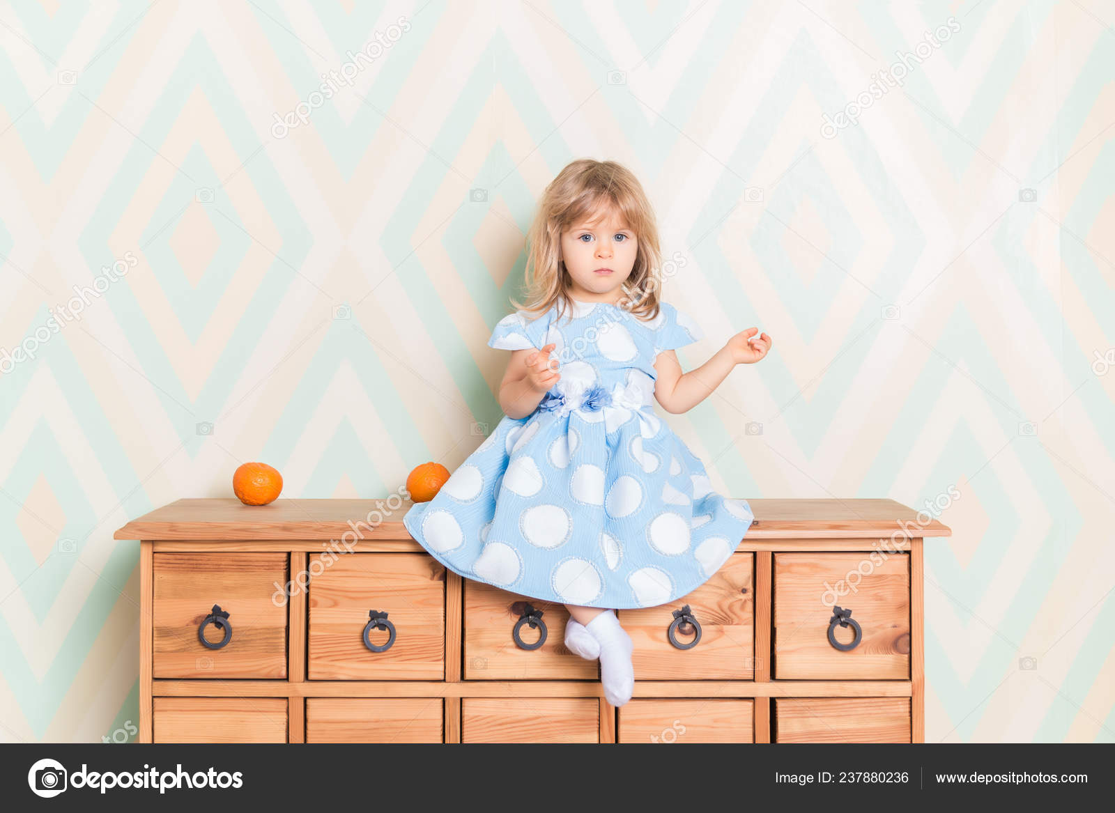 A Little Baby Girl In Her Room Sitting Cross Legged On Chest Of