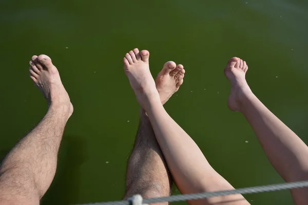 female and male feet above the water