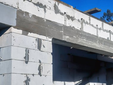 İnşaat halindeki bir binanın yakın görüntüsü beton blokların ve kirişlerin açık mavi gökyüzüne karşı yapısını ve yapısını gözler önüne seriyor..