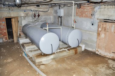 Industrial basement featuring a pair of cylindrical tanks, a door, and various pipes, all within a concrete and brick environment. grainy texture