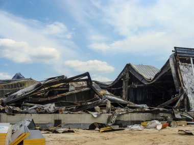 A building destroyed by fire stands against a cloudy sky, showcasing devastation and structural damage.
