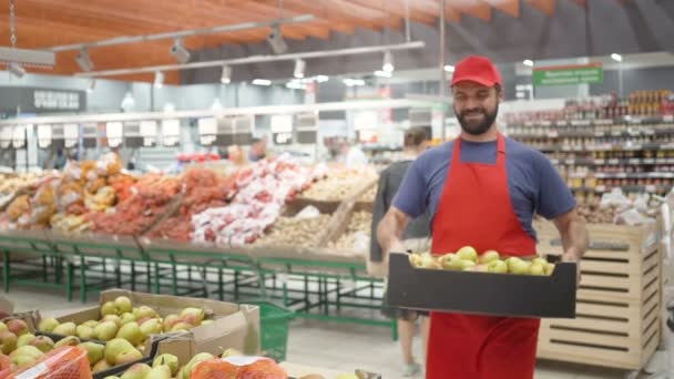 Petugas supermarket laki-laki mengisi kotak dengan pir di departemen sayuran — Stok Video