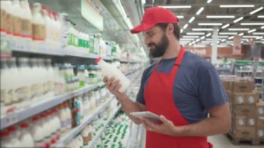Yakışıklı erkek merchandiser süt ürünleri dijital tablet ile kontrol