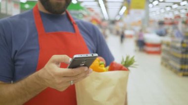 teslimatçı kağıt torbaları süpermarkette bir smartphone kullanarak bir emir alan ile