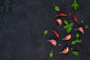 Yemek pişirmek için malzemeler. Koyu arka plan üzerine sarımsak, fesleğen ve kırmızı biber üstten görünüm.