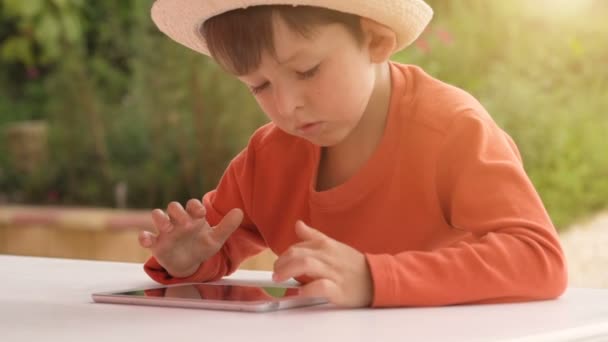 Child playing with digital tablet on summer nature background — Stock Video