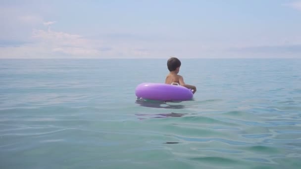 Niedlicher kleiner Junge schwimmt auf aufblasbarem Ring im Meer — Stockvideo