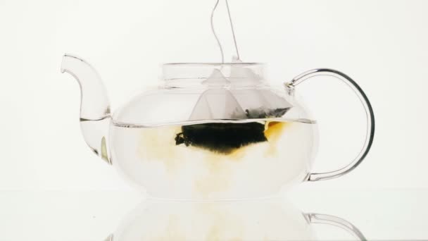 Teapot glass with two tea bags on a white background — Stock Video