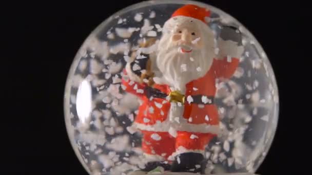 Санта-Клаус в снежном шаре на черном фоне — стоковое видео