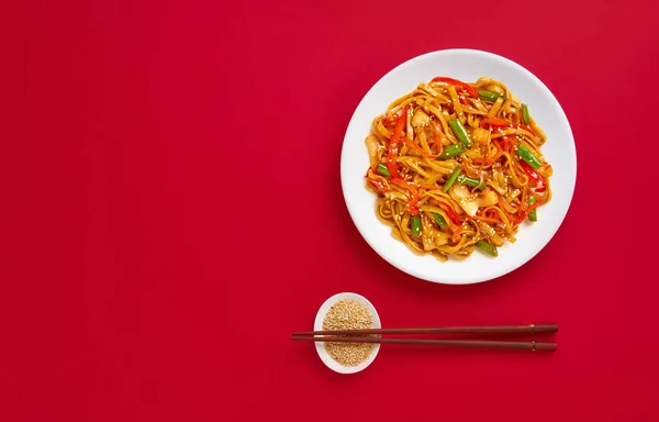 Fry noodles sebze ile karıştırın. Asya vegan gıda üzerinde kırmızı bir arka plan, düz yatıyordu ve kopya alanı.