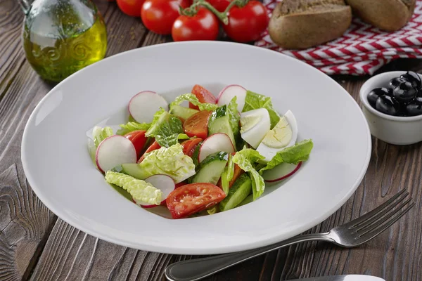 Zeleninový salát s vejci, rajčaty a salátem v bílé desky na dřevěné pozadí — Stock fotografie