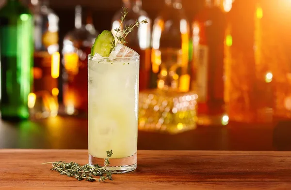 Cocktail con ghiaccio e lime su un bancone di legno scuro, bokeh sfondo luminoso — Foto Stock
