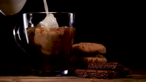 在黑暗的背景下将牛奶倒进一杯冷煮咖啡中 — 图库视频影像