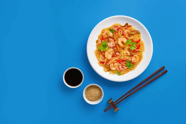 Macarrão de vidro de arroz delicioso com camarões e legumes no fundo azul. Deitado plano com vista superior — Fotografia de Stock