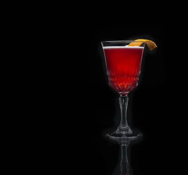 Glass of cosmopolitan cocktail decorated with orange on black background. — Stock Photo, Image