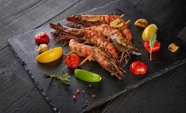 Barbekü ızgara karides baharatlı malzemeler sarımsak ve domates koyu ahşap tablo