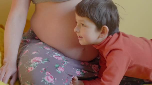 Pequeño niño escuchando mamá embarazada vientre — Vídeos de Stock