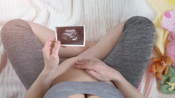 Zwangere vrouw bedrijf echografie beeld. Concept van de zwangerschap. Bovenaanzicht — Stockvideo