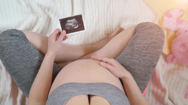 Mujer embarazada sosteniendo imagen de ultrasonido. Concepto de embarazo. Vista superior — Vídeos de Stock