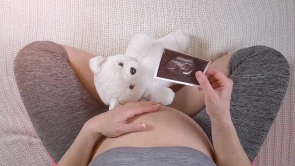 Pregnant woman holding ultrasound photos of fetus — Stock Video