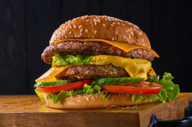 Ev yapımı sığır eti burger marul ve domates closeup ahşap kesme tahtası üzerinde servis. Koyu arka plan