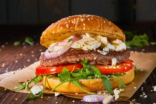 Hamburguesa casera de res con rúcula y tomates servida sobre fondo de madera —  Fotos de Stock