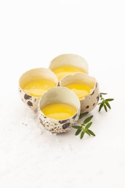 Beyaz arka planda sarısı ve otlar ile ham bıldırcın yumurtaları