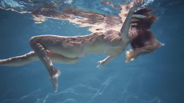 Сексуальная женщина в нижнем белье, плавающая в голубой воде — стоковое видео