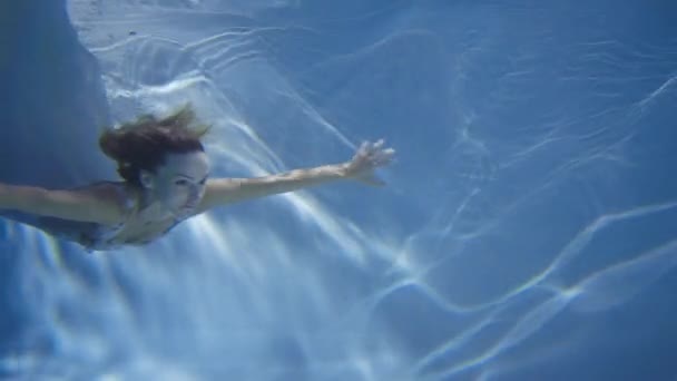 Een vrouw in een witte jurk als een zeemeermin zwemmen onder water. — Stockvideo