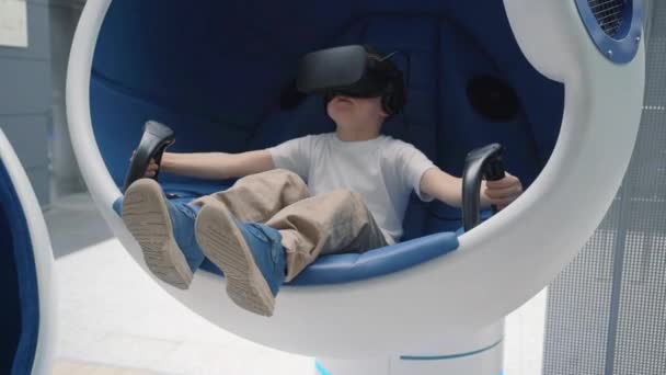 Little boy playing virtual reality in a moving interactive chair — Stock Video