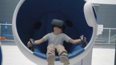 Hareketli interaktif sandalyede sanal gerçeklik kulaklı çocuk