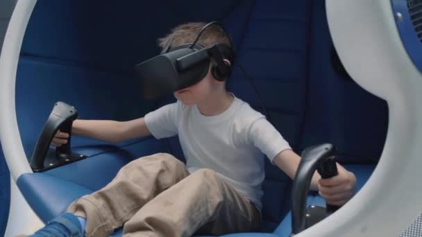 Jongen genieten van Virtual Reality Attraction met behulp van VR-headset in een bewegende interactieve stoel — Stockvideo