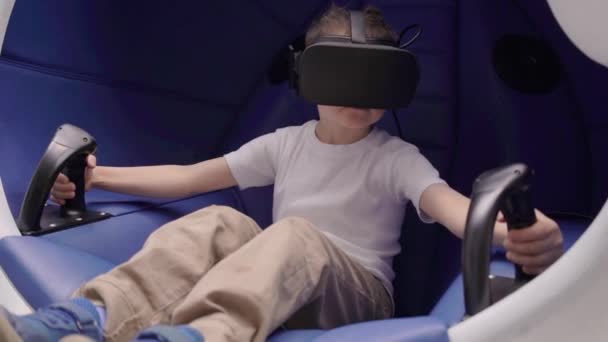 Petit garçon jouant à la réalité virtuelle dans une chaise interactive en mouvement — Video