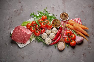 Baharatlar ve biberiye ile çiğ sığır. Sağlıklı pişirme için taze malzemeler