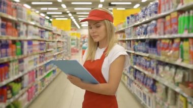 Pretty hırdavatçı işçi pano tutan ve süpermarketraflar arasında ayakta