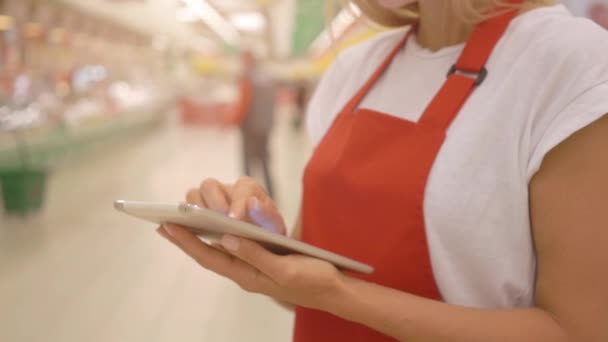 Female supermarket clerk using apps on a digital tablet, innovative technology and work concept, — Stock Video