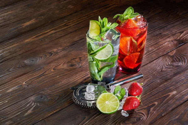 Mojito cocktails med lime, jordgubb och mynta i glas med isbitar på trä bakgrund — Stockfoto
