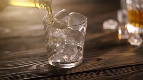 Бармен наливает виски из бутылки в стекло на деревенский деревянный стол — стоковое видео