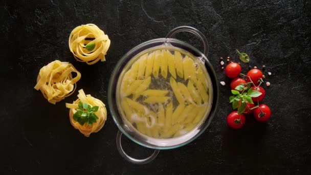 Matlagning pasta penne i en glas gryta med kokande vatten — Stockvideo