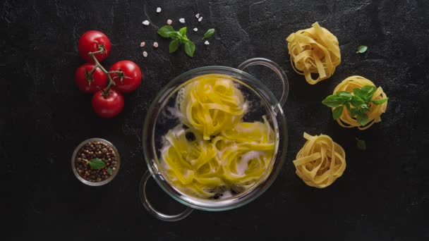 Cinemagraph-Tagliatelle pasta matlagning i kokande vatten på träbord — Stockvideo