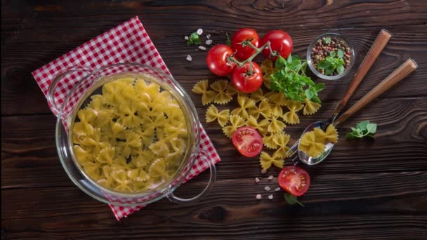 Cinemagraph - pasta cocida en agua hirviendo en maceta de vidrio sobre mesa de madera — Vídeo de stock