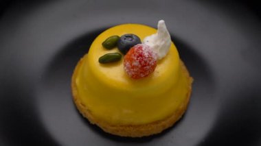 Siyah tabakta dönen sarı sır ile kaplı Mango mus kek tatlısı