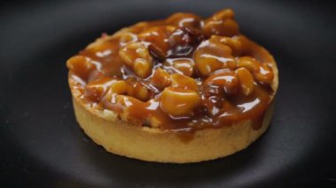Siyah plaka üzerinde dönen fındık ve karamel ile Tart