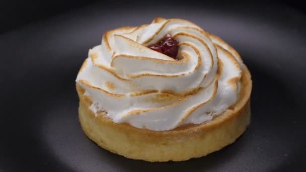 Lemon tartlet with meringue on black plate rotating 360 — Stock Video